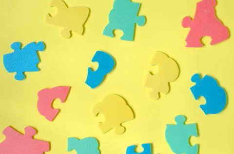 Elements of a multi-colored puzzle on a yellow background Stock Photos