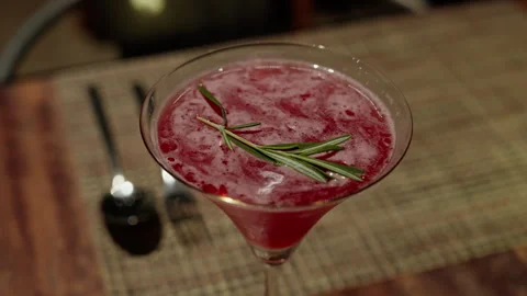 Elevate your sensory experience with a pink cocktail crowned by a sprig of Video stock 248579425