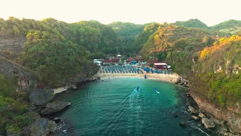 Elevated aerial view reveals a secluded turquoise lagoon surrounded by rugg.. Video stock 341547656