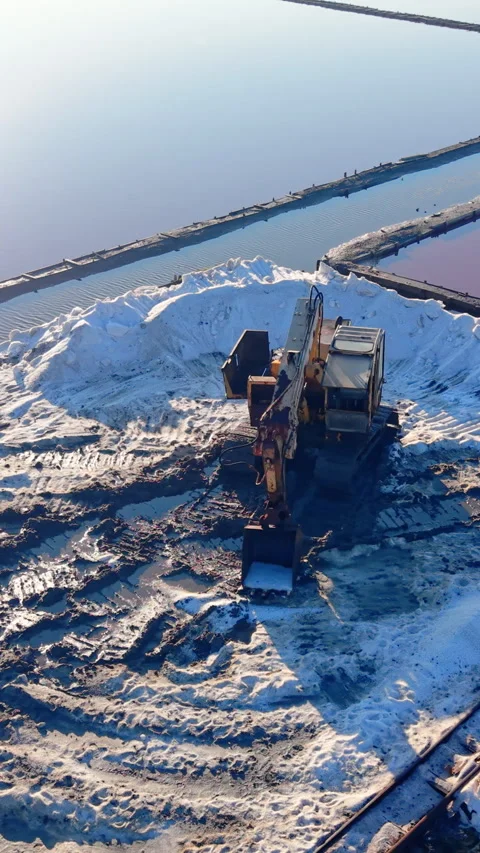 Elevated angle of excavator scooping salt mound, Pomorie, Bulgaria Vertical Stock Footage 338007284