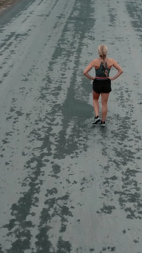 Elevated back view of female runner slowing to a walk Stock Footage 340047013
