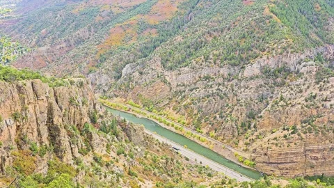 Elevated canyon viewpoint overlooks a river and parallel highway winding Stock Footage 345254784