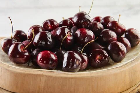 Elevated Elegance, Fresh Cherries Presented on Wooden Stand and Concrete. Summer Stock Photos