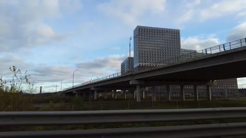 An elevated highway spans over open ground with distant city blocks, supported Video stock 325839835