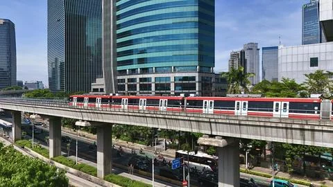 Elevated Light Rail Train Passing Through Modern Cityscape Stockfoto's