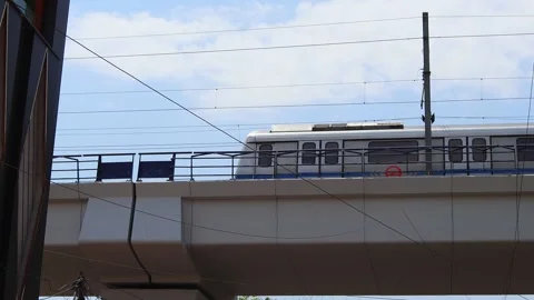 Elevated metro train passing on above-ground track in New Delhi, India Stock Footage 321998143