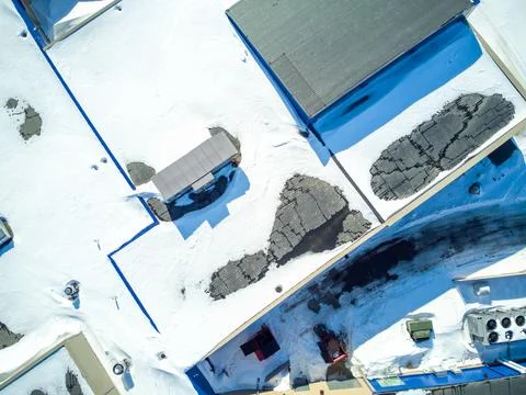Elevated overhead drone view of a flat roofed building with snow load and Stock Photos