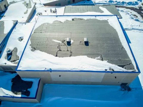 Elevated overhead drone view of a flat roofed building with snow load and ... Foto stock