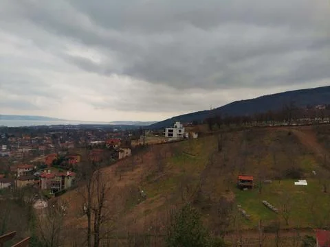 Elevated panoramic view over a sloping hillside with bare trees and residential Stock Photos