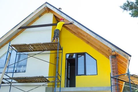 Elevated perspective of worker adjusting upright timber under eave, multi-s.. Stock Photos