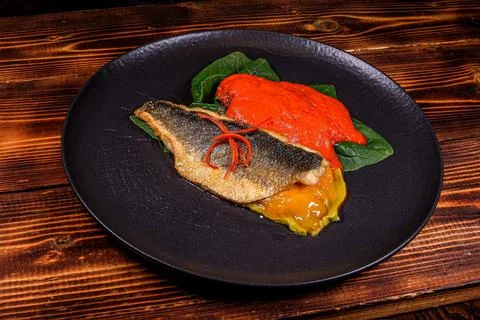 Elevated shot: Balanced dish with pan-fried fish, spinach and red sauce 스톡 사진