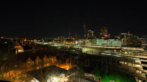 Elevated time lapse shot of trains in front of cityscape, night Stock Footage 99284037