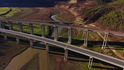 Elevated train tracks cross over a winding river in a rural area Vidéo 336547250
