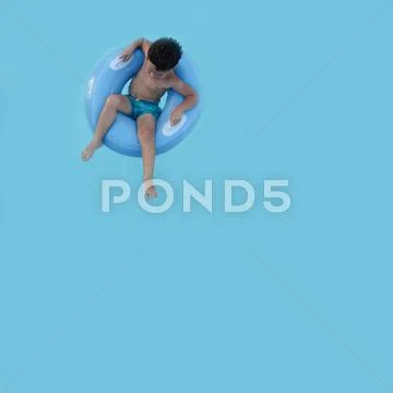 Elevated view of boy (4-5) sitting in rubber ring in swimming pool Stock Photos