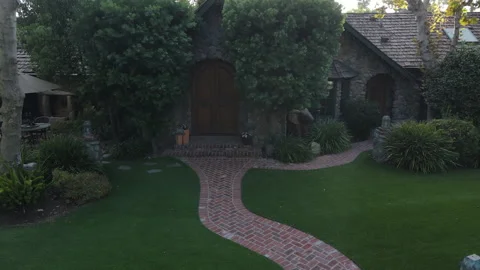 Elevated view of a brick path leading to a stone cottage door Stock Footage 345546548