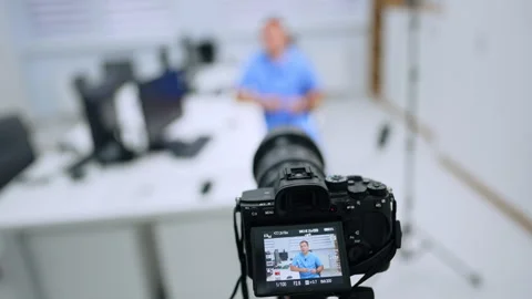 Elevated view of a camera filming a medical presenter. A rear monitor shows a Stock Footage 346615216