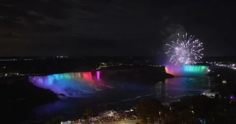 Elevated view of fireworks above multi colored illuminated Niagara falls Stock Footage 251289649