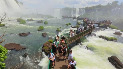 Elevated view of Iguazu walkway filled with tourists above rushing water and Stock Footage 327640345
