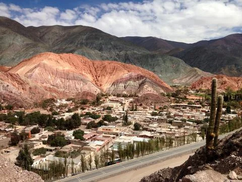 Elevated view of multi-coloured hill with small town nestled in foreground Stock Photos