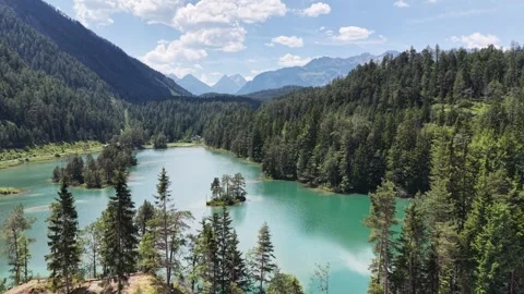 Elevated view overlooks Weissensee beyond a roadside foreground and forested Stock Footage 347128952