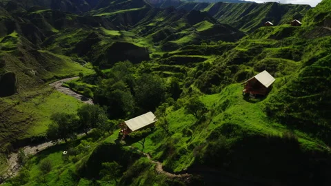 Elevated view of rural valley with cabins, a dirt road, and a car, evoking Stock Footage 268464193