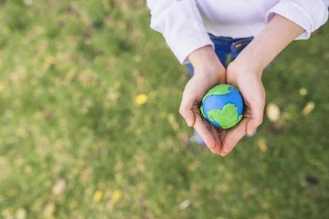 Elevated view small clay globe cupped hands grass Resolution and high quality Stock Photos