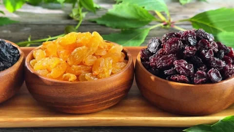 Elevated view of three raisin varieties in wooden bowls with grapevine foli.. Stock Footage 339462617