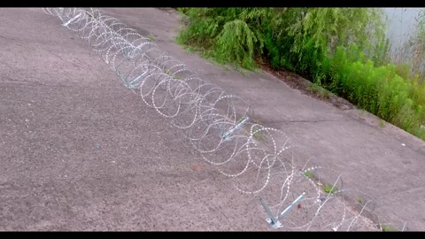 Elevated Wide View Along Razor Wire Barrier and Vegetation Stock-Footage 344122813
