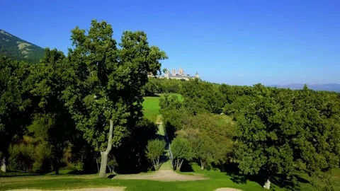 Elevation above a wooded golf course with the monumental palace of the monastery Stock Footage 168735787