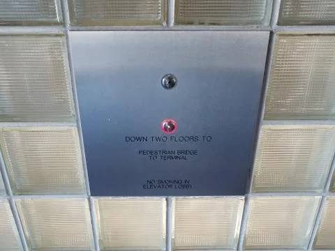 Elevator button and sign down two floors to pedestrian bridge Foto stock
