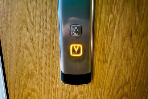 Elevator button with a glowing letter V. 스톡 사진