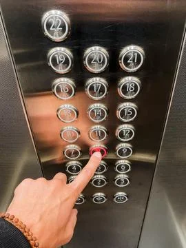 An elevator button panel featuring a hand actively pressing the button for .. Foto stock