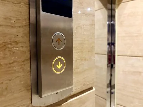 Elevator buttons with illuminated arrows on a marble wall. 스톡 사진