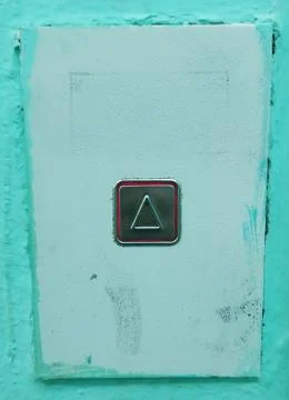 The Elevator call button pressed and glowing red on the turquoise painted wal Stock Photos