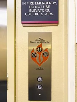 Elevator control panel advising not to use elevators in case of fire. Stock Photos
