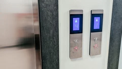 Elevator control panel with two buttons. One button is illuminated blue, Stock Photos
