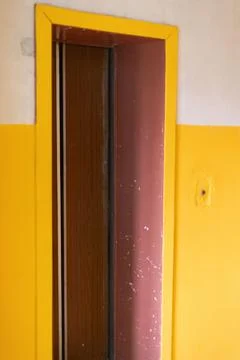 An elevator door in a deteriorating building with visible wear and peeling pa Stock Photos