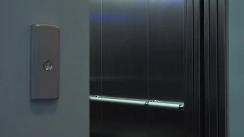 An elevator door slides open and a man walks out - closeup Stock Footage