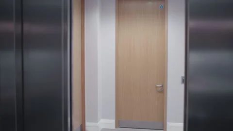 Elevator doors open to bright office apartment doors and corridor Stock Footage 257825614