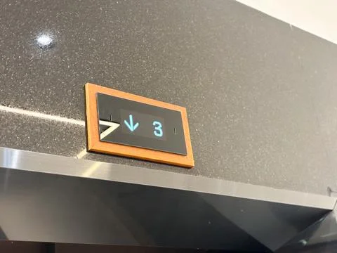 Elevator floor indicator showing down arrow number three black granite wall. Stock Photos