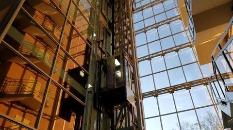 Elevator moving in modern corporate building in sunset golden hour sunlight Stock Photos