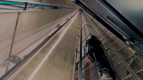 Elevator technician working inside a shaft, looking up, camera moving slowly 動画素材 333934173