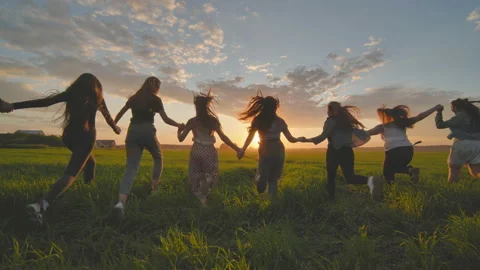 Eleven cheerful girls run to meet the sun across the field in summer holding Stock Footage 160411390
