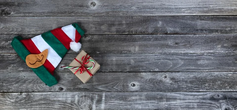 Elf cap and giftbox plus candy cane on faded wood for merry Christmas Stock Photos