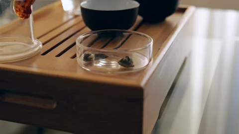 Elite Chinese white tea. twisted tea leaves fall on a glass flask Stock Footage 220341706