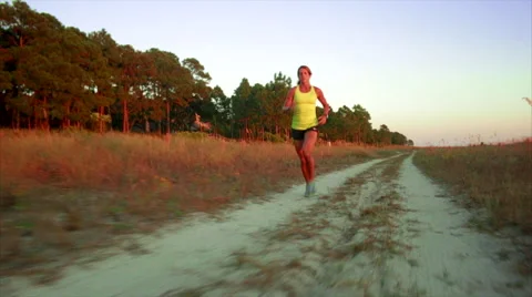 Elite Runner Runs on sandy road by ocean in dunes Stock Footage 62892517