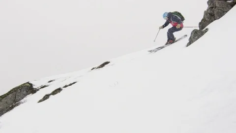 Elite skier cruising down a remote mountain peak during a snow storm Stock Footage 113229072