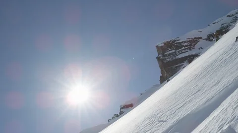 Elite skier cruising down a remote mountain, with sun in the background Stock Footage 113259246
