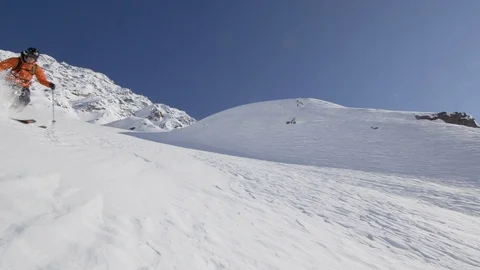 Elite skier cutting through fresh powder on a remote mountain with lens flare Stock Footage 113241464