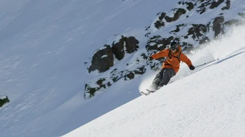 Elite skier cutting through fresh powder on a rocky mountain Stock Footage 113244497